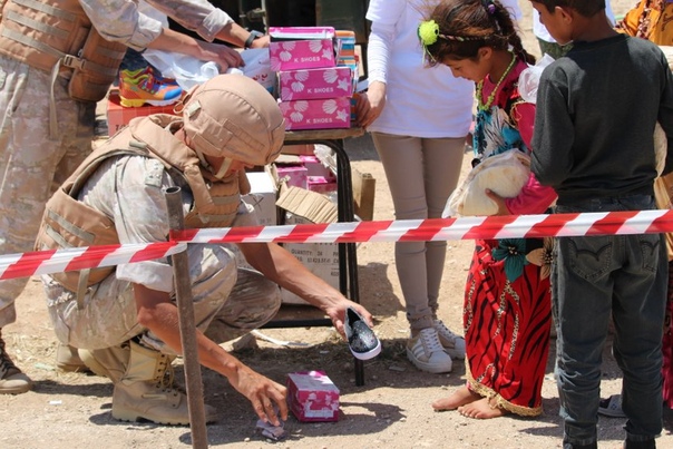 Боец российской военной полиции обувает сирийскую девочку в районе г. Абу Духур
